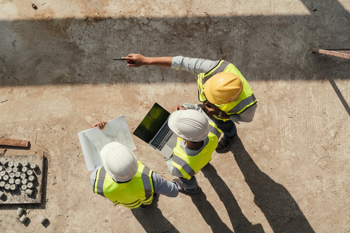 Construction team reviewing plans on a laptop at a jobsite