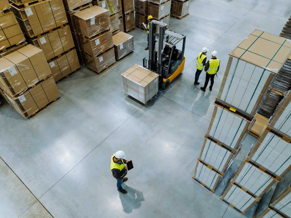 Workers coordinating on a warehouse floor with a forklift