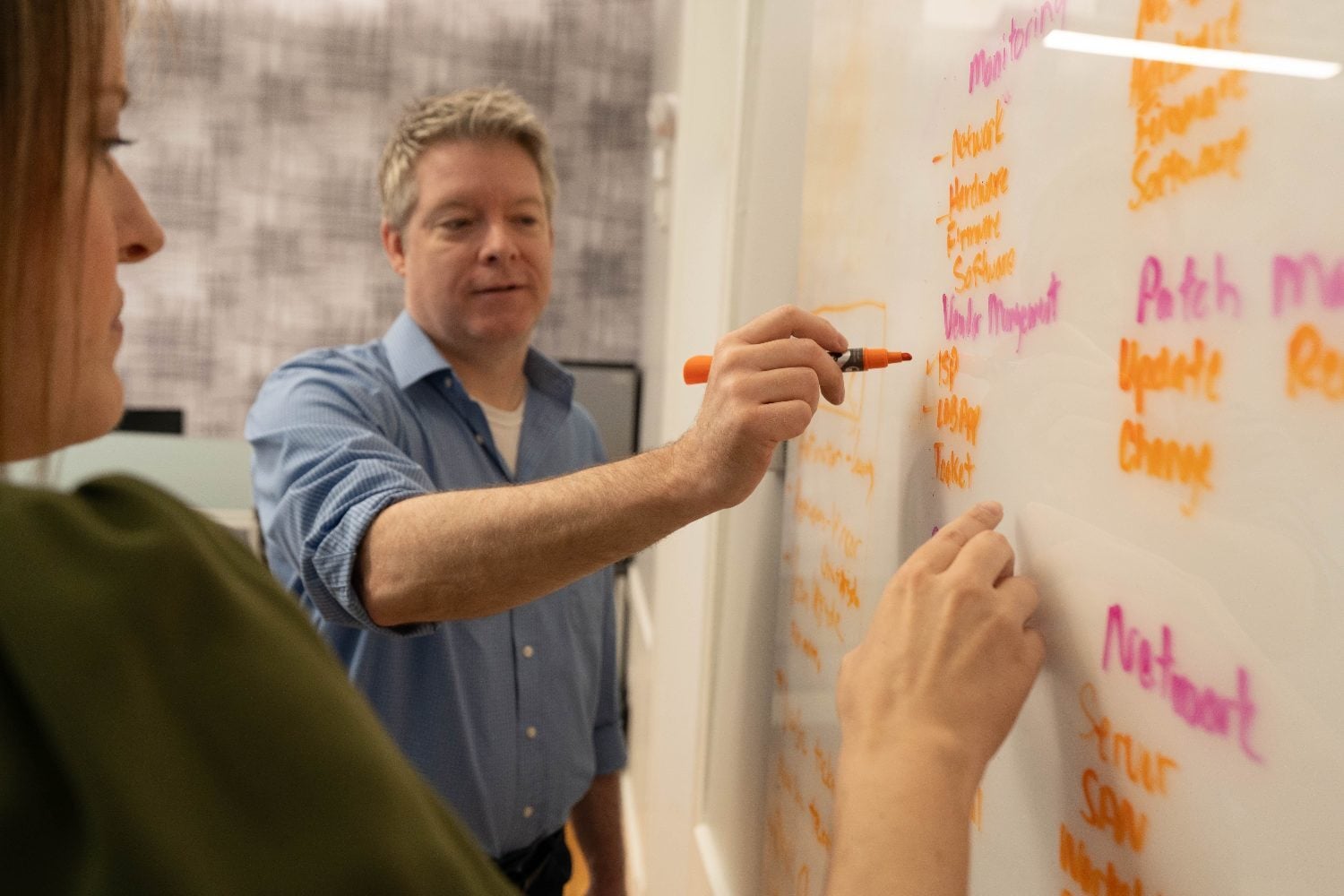Two Winsor consultants mapping a client network on a whiteboard during an infrastructure assessment
