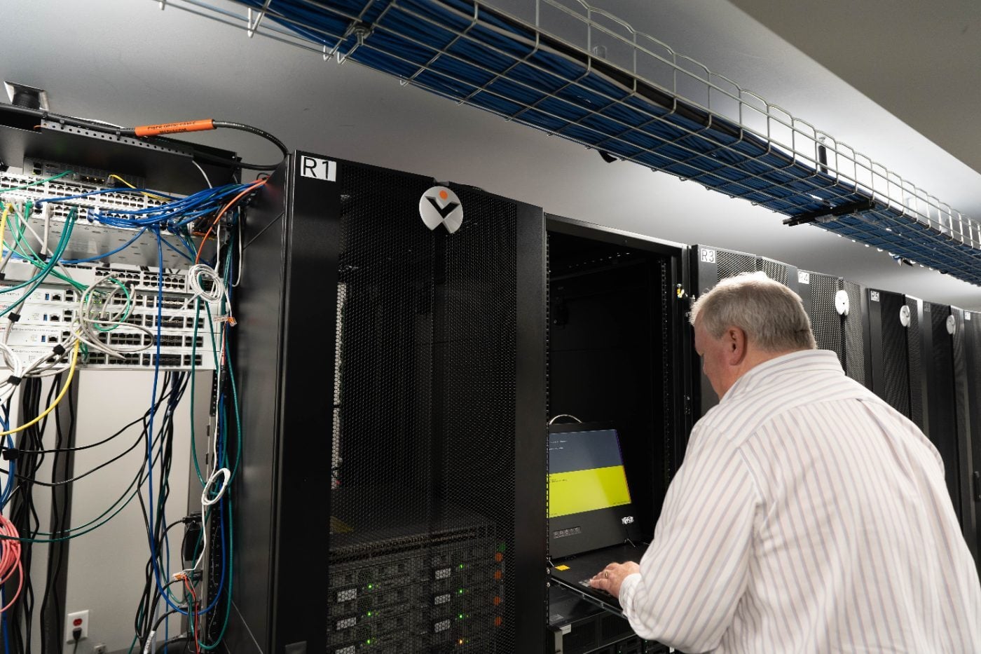 Winsor engineer working in a labeled server rack room with structured cabling and fiber